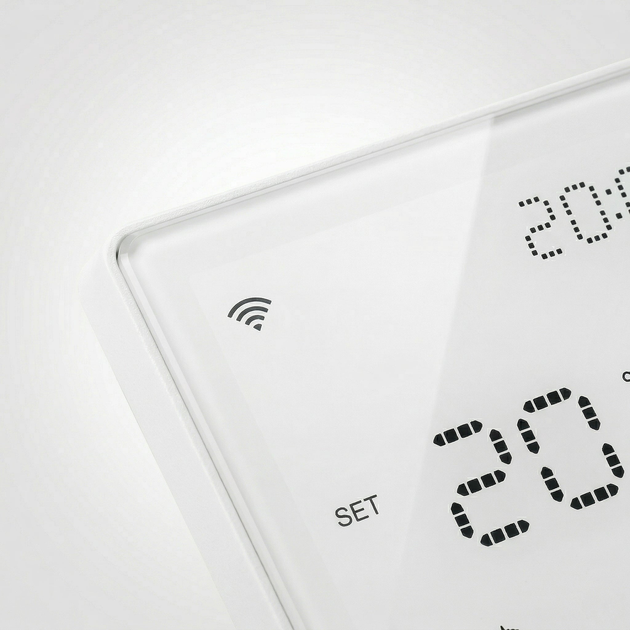 Gros plan sur le thermostat mural NéoPure Comfort blanc pur avec symbole Wi‑Fi et affichage LED.
