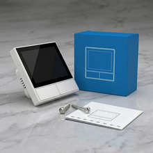 NéoHub Touch blanc avec boîte bleue, accessoires et notice.
