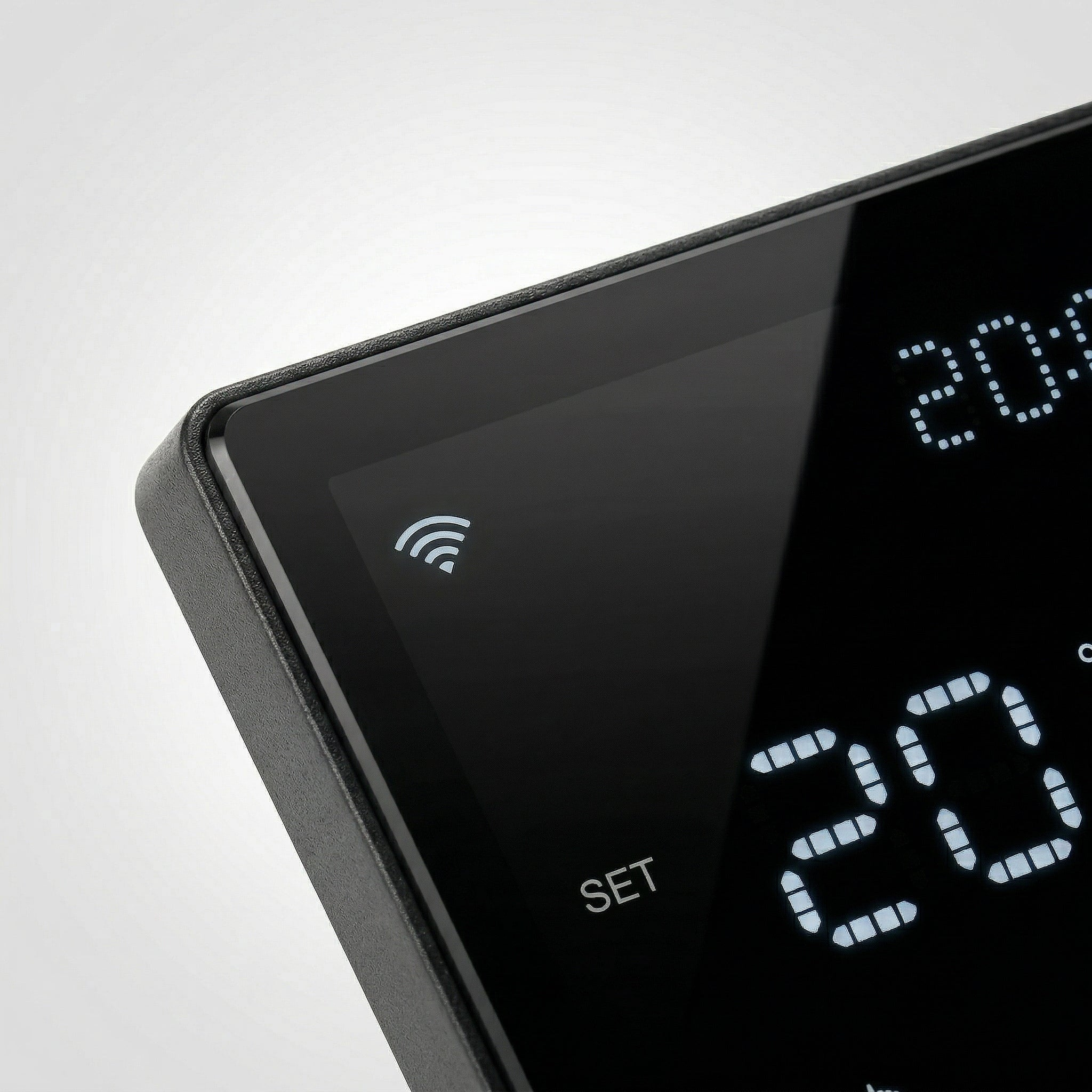 Gros plan du thermostat mural intelligent NéoPure Comfort noir sur fond blanc, avec écran LED et symbole de connexion sans fil.