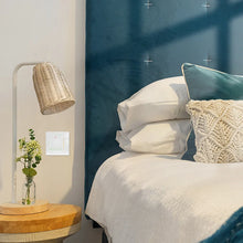 NéoStation Comfort blanc installé près d'un lit dans une chambre moderne avec lampe de chevet.