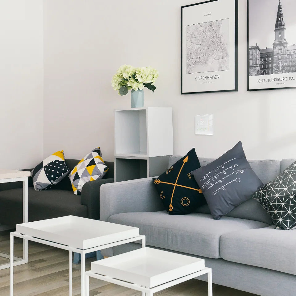 NéoStation Comfort blanc installé au mur dans un salon lumineux avec canapé gris.