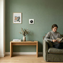 Thermostat mural installé dans un salon avec mur vert.